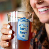Woman holding a glass of beer with a 'drink local beer' label.